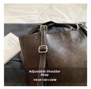 Detail of adjustable shoulder strap and white stitching on brown leather tote bag
