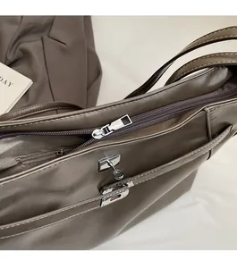 Detail of smooth silver zipper and metallic clasp on dark brown leather tote bag