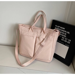 Detail view of pink quilted tote bag with front pockets and adjustable shoulder strap