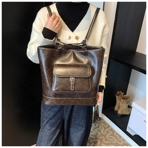 Detail of dark brown leather tote bag with white contrast stitching and buckle pocket