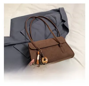 Detail of dark brown suede shoulder bag featuring a tassel and marble donut charm