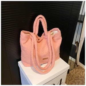 Close-up of pink faux shearling tote bag featuring detailed soft texture and brand label