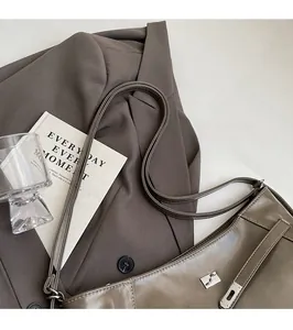 Détail d'un sac bandoulière marron foncé avec fermoir rotatif argenté et finition cuir lisse