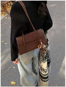 Detail of vintage brown suede shoulder bag with dual straps and donut charm decoration