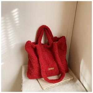 Detail shot of the red plush tote bag showing the soft faux fur texture and branded leather label