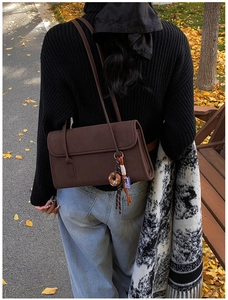 Outdoor shot of a vintage brown matte shoulder bag with a colorful tassel keychain