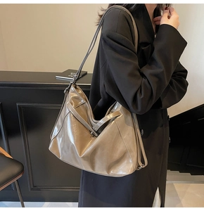 Detail view of large brown vintage tote bag in glossy leather worn by a model