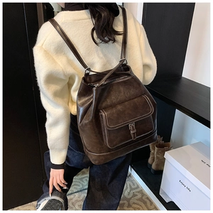 Detail view of coffee brown vintage leather backpack with contrast stitching on model