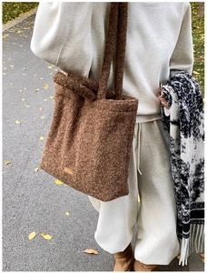 Detailed texture of brown plush tote bag with orange label on outdoor autumn path