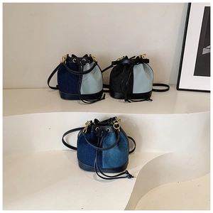 Three patchwork denim bucket bags with leather straps displayed on a white podium
