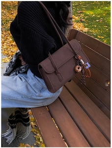 Detail view of dark brown frosted shoulder bag with donut charm and side logo tag
