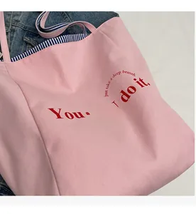 Detailaufnahme der rosa Canvas-Tragetasche mit Aufdruck und blau gestreiften Gurten