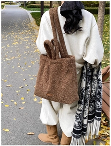 Detail of soft brown plush tote bag showing dual strap design in an autumn park setting