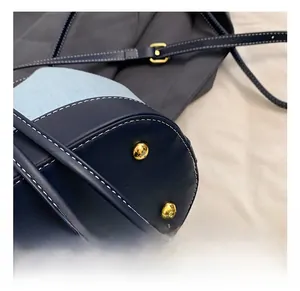 Close-up of golden hardware rivets and contrast white stitching on blue bucket bag