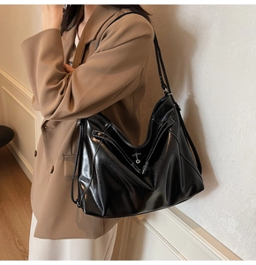 Detail of high-gloss black leather tote bag with contrast stitching and silver ring buckle
