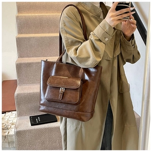 Detail of vintage brown leather tote bag with functional metal buckle front pocket