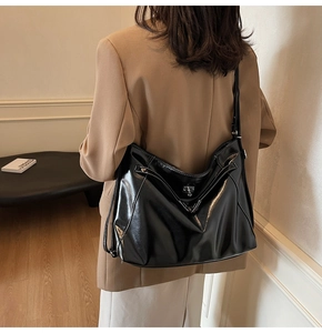 Detail of black leather tote bag with white contrast stitching and silver buckle accent