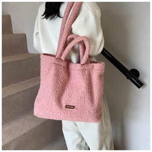 Detailed shot of pink plush tote bag with textured handles and brown leather label