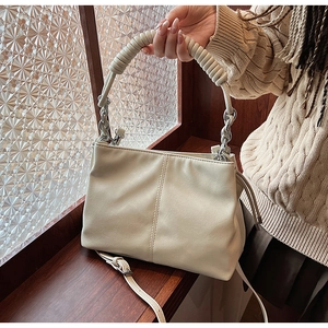 Dettaglio della borsa a secchiello beige con manico a spirale e catena in metallo