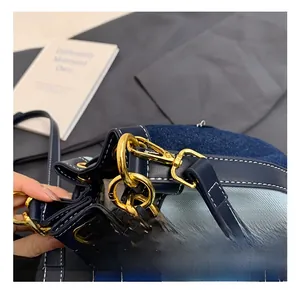 Close-up of golden hardware hooks and navy blue denim fabric with white stitching details