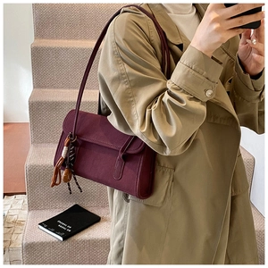 Detail of burgundy vintage shoulder bag styled with an elegant khaki trench coat