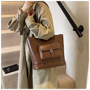 Close-up of a vintage brown tote bag with buckle pocket detail and matte leather texture