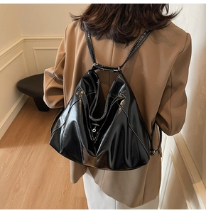 Glossy black patent leather tote bag styled with beige blazer in minimalist indoor setting