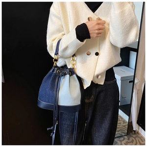 Detail of blue denim patchwork bucket bag with drawstring closure and gold metal hardware