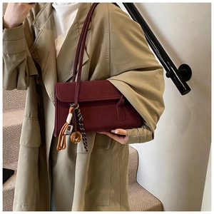 Close-up of matte wine red shoulder bag with retro charm worn by a model in a trench coat