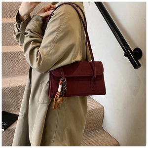 Detail of vintage matte burgundy shoulder bag with an elegant woven tassel accessory