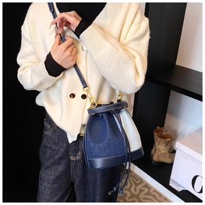 Detail of blue denim patchwork bucket bag with drawstring and golden hardware