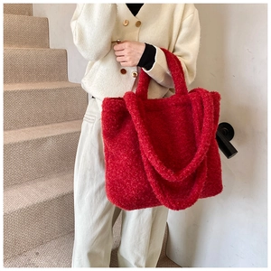 Detail of red plush tote bag with soft faux shearling texture and dual strap design
