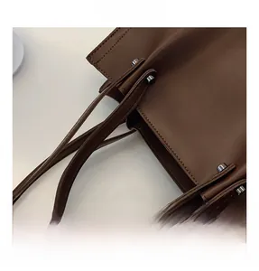 Detail shot of dark brown leather tote bag showing sturdy handle and silver metal hardware