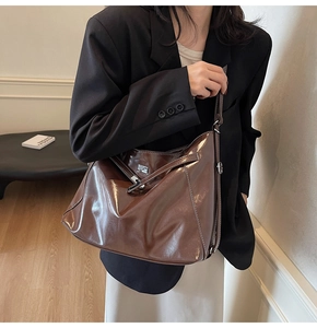Close-up of a brown oily leather tote bag with silver buckle worn by a model