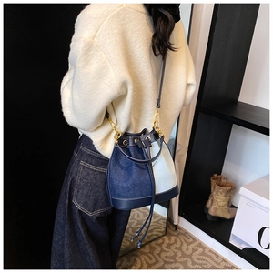 Detailed view of bicolor denim bucket bag with drawstring closure and gold hardware