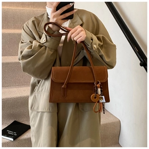 Close-up of vintage brown frosted baguette bag with wooden tag and slim shoulder straps