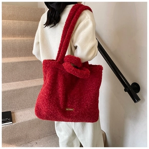 Detail view of red fluffy plush tote bag showing soft texture and faux leather logo patch