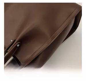 Detail shot of sturdy double topstitching and silver rivets on dark brown leather tote bag