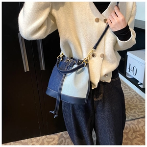 Fashionable denim bucket bag with leather trim shown on a model for scale and style