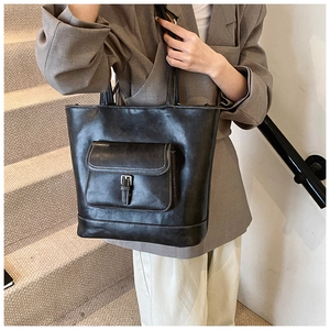 Detail of black leather tote bag featuring white contrast stitching and buckle front pocket