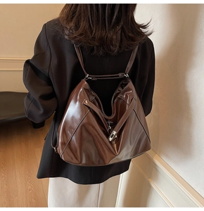 Detail of a deep brown glossy PU leather tote bag worn by a model in a casual indoor setting