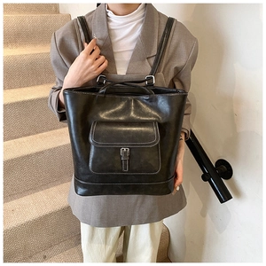 Detail shot of a black leather tote backpack with white contrast stitching on stairs