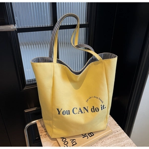 Nahaufnahme der gelben Canvas-Tasche mit inspirierendem Text und gestreiftem Innenfutter