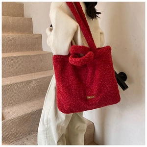 Detail of red plush tote bag with our fave label shown by model on stairs