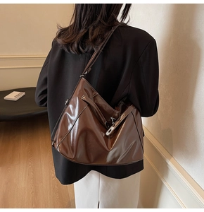 Macro shot of dark brown patent leather hobo bag with silver hardware and stitching
