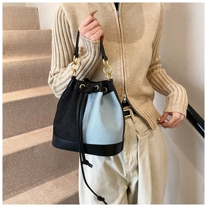Detail of blue and black color-block bucket bag with drawstring and gold metal rings