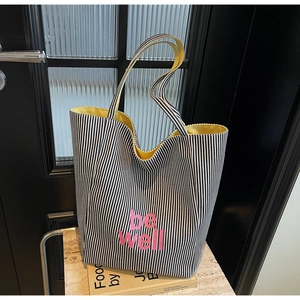 Detail der Canvas-Tasche mit schwarzen Streifen, rosa Text und gelbem Kontrastfutter