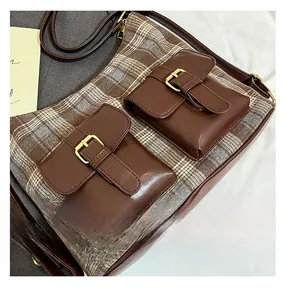 Detail view of double front pockets with gold buckles on brown plaid shoulder bag