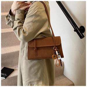 Detail view of a vintage frosted brown shoulder bag with a decorative tassel pendant
