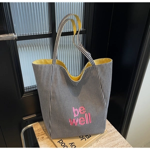 Detail der gestreiften Canvas-Tasche mit be well Aufdruck und gelbem Innenfutter